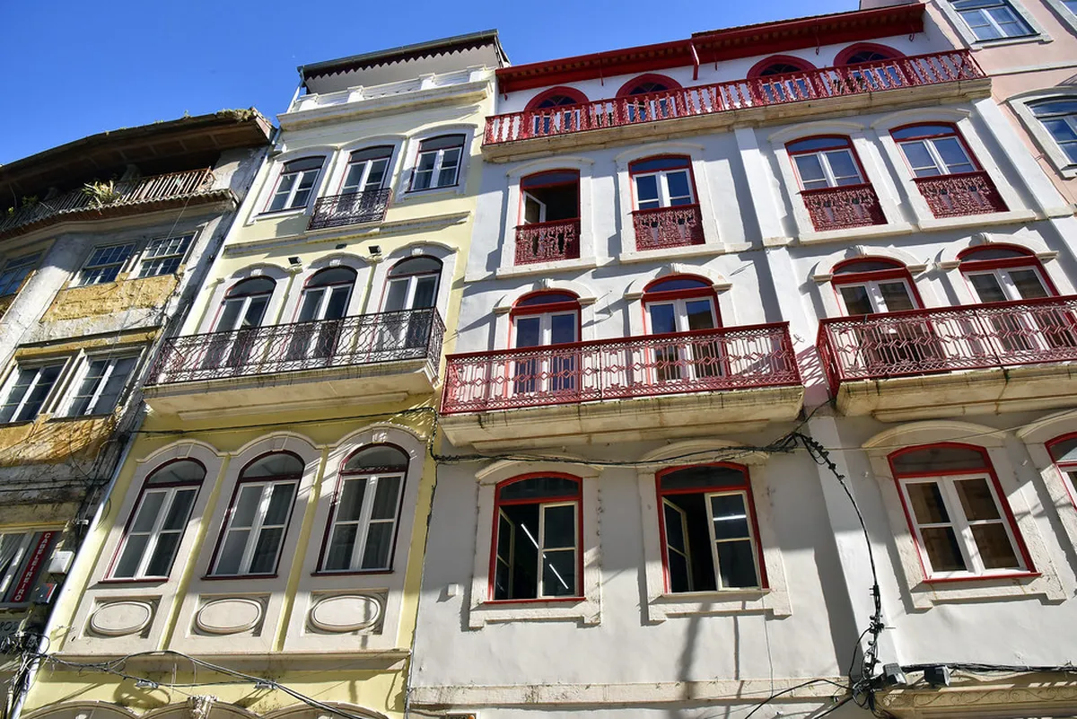 Narrow medieval alleyway in Coimbra's Judiaria quarter with stone walls and traditional architecture
