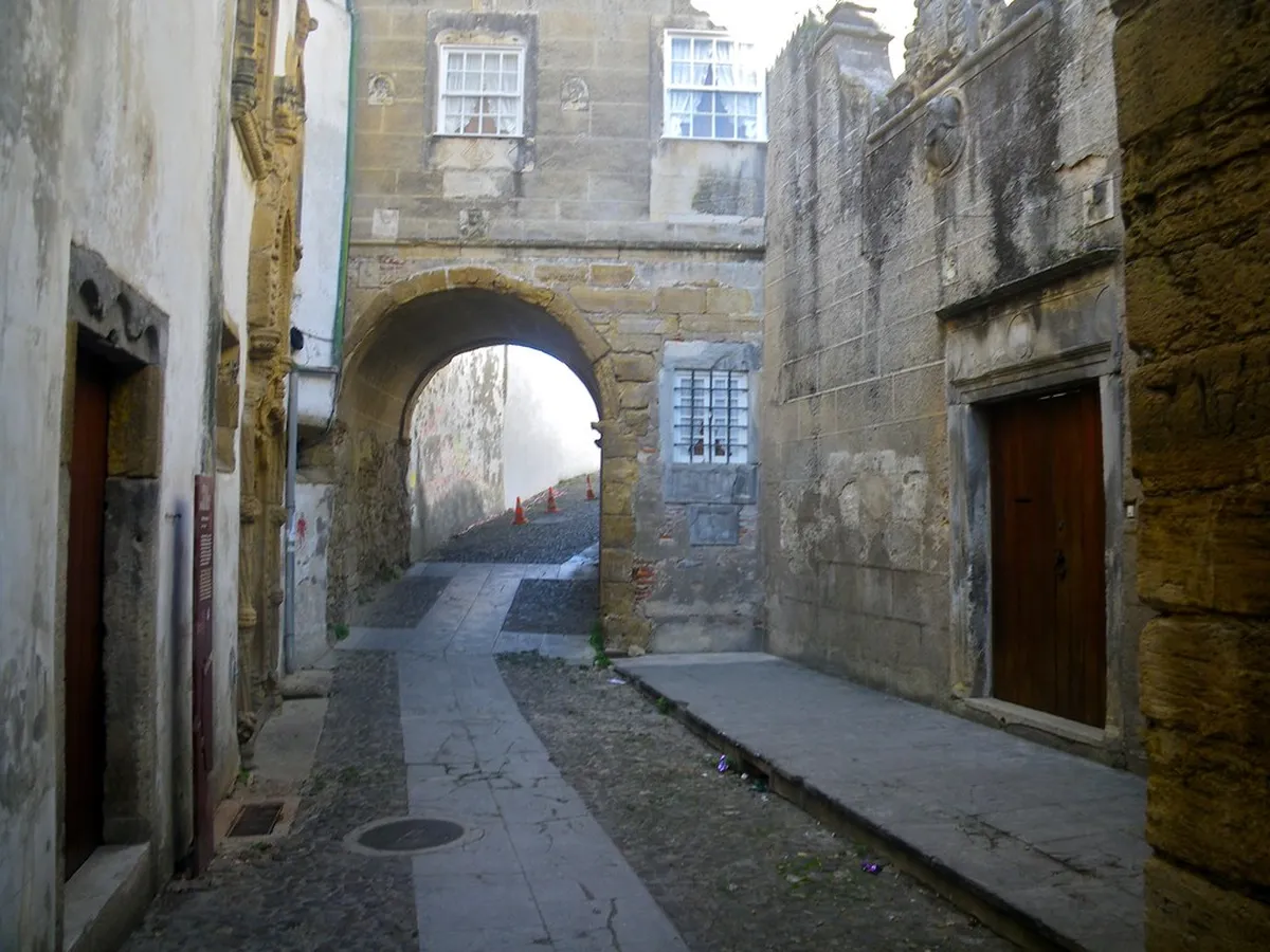 Narrow cobblestone medieval streets in Coimbra lined with historic stone buildings and archways