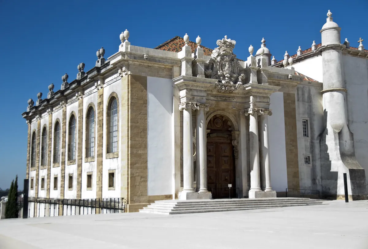 The ornate Baroque interior of the Biblioteca Joanina at Coimbra University, featuring gilded bookshelves