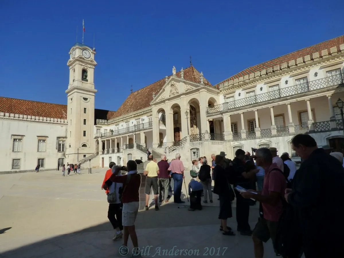 Coimbra's Baroque university tower and historic stone buildings viewed from the old town hillside