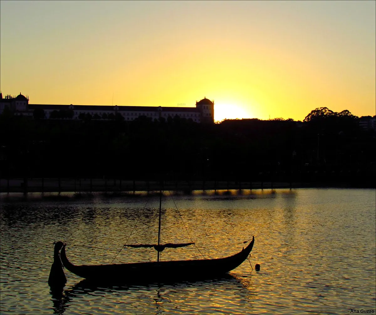 Coimbra Old Town skyline reflected in the Mondego River with historic buildings rising up the hillside
