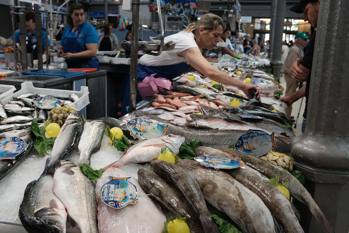Open-air food market in Coimbra with stalls selling fresh produce, regional cheeses, and local delicacies