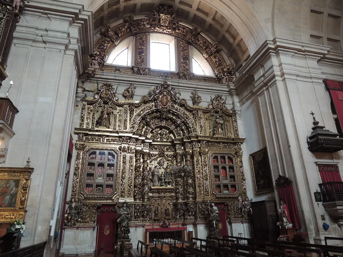 Interior of Coimbra's New Cathedral showing ornate gilded altarpiece and vaulted Baroque nave