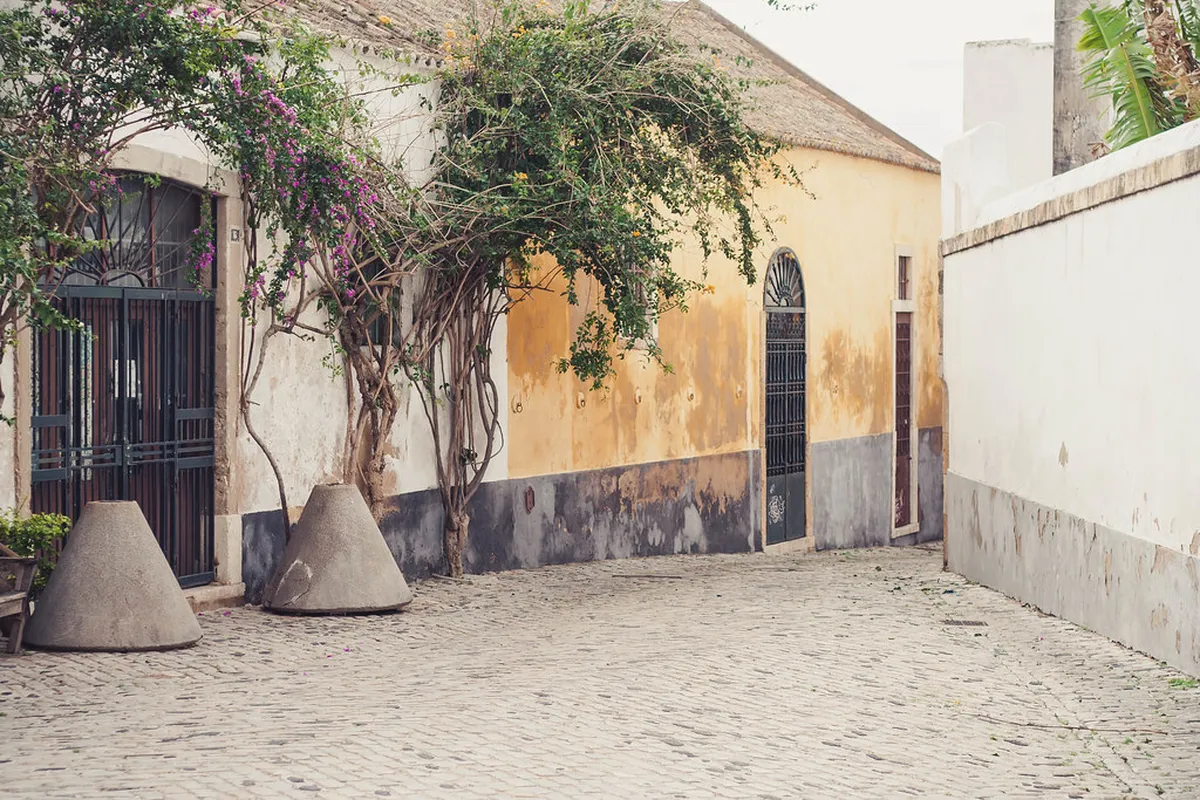 Narrow cobblestone street winding through Faro old town historic quarter with traditional white buildings