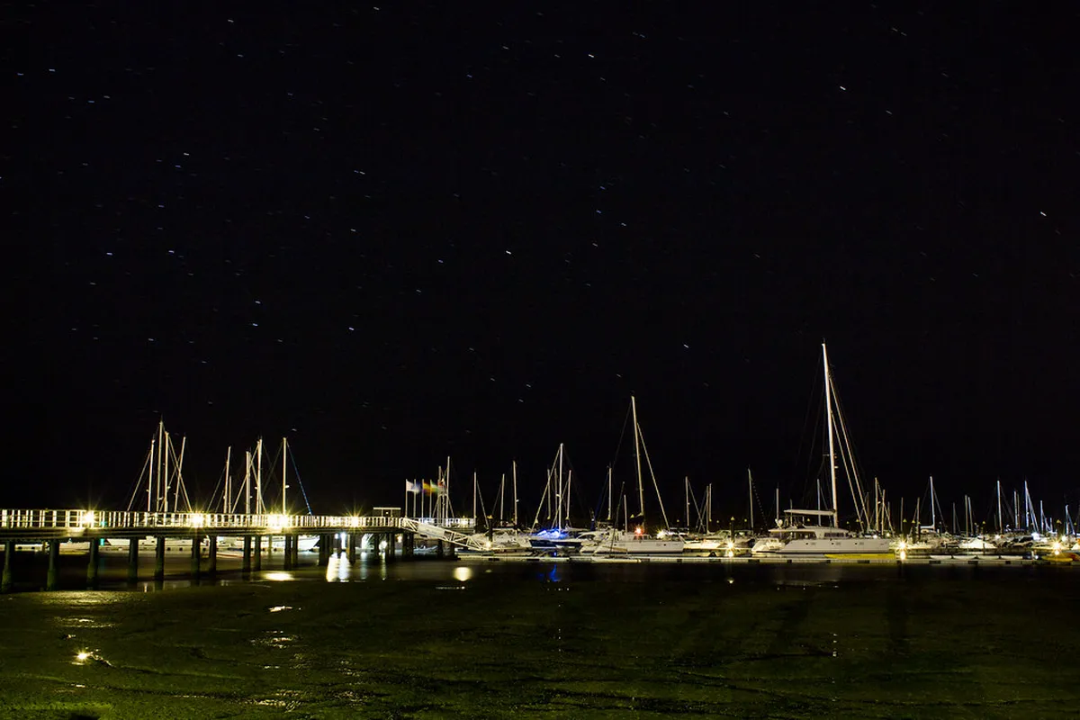 Faro harbour at night with moored boats reflecting lights on the calm water of Ria Formosa