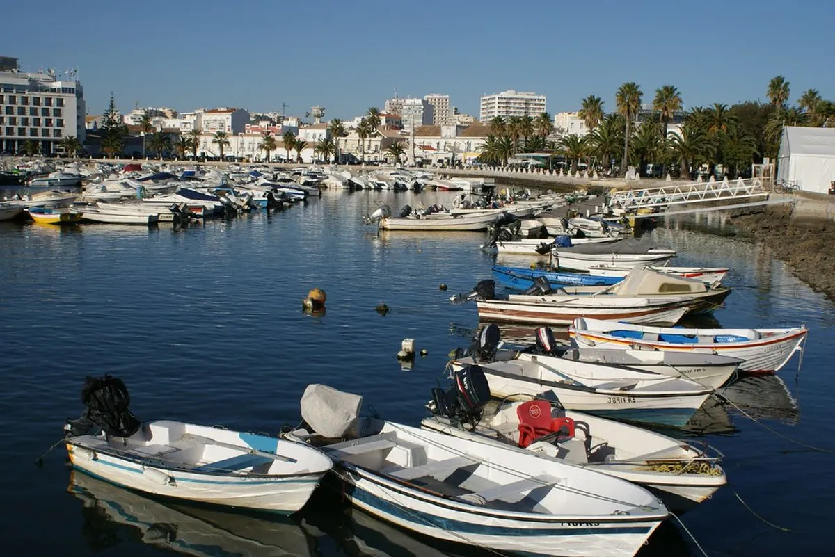 Faro Marina waterfront promenade with moored boats and the old town backdrop at dusk
