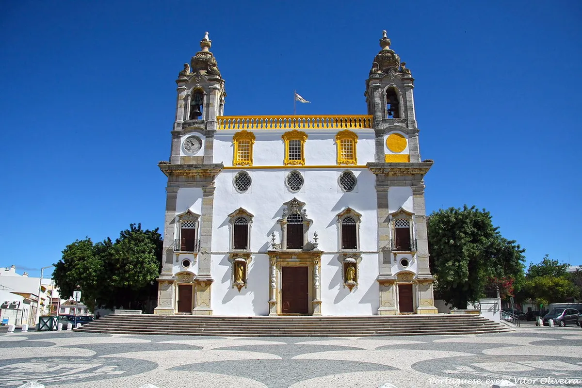 Facade of the Igreja do Carmo church in Faro with ornate Baroque stonework and twin bell towers