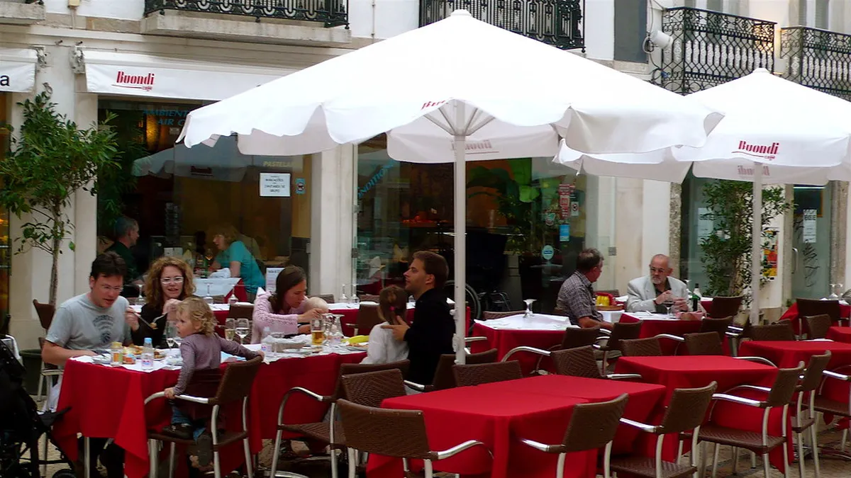 Outdoor cafe terrace in Faro's historic old town with traditional Portuguese architecture and cobblestone street