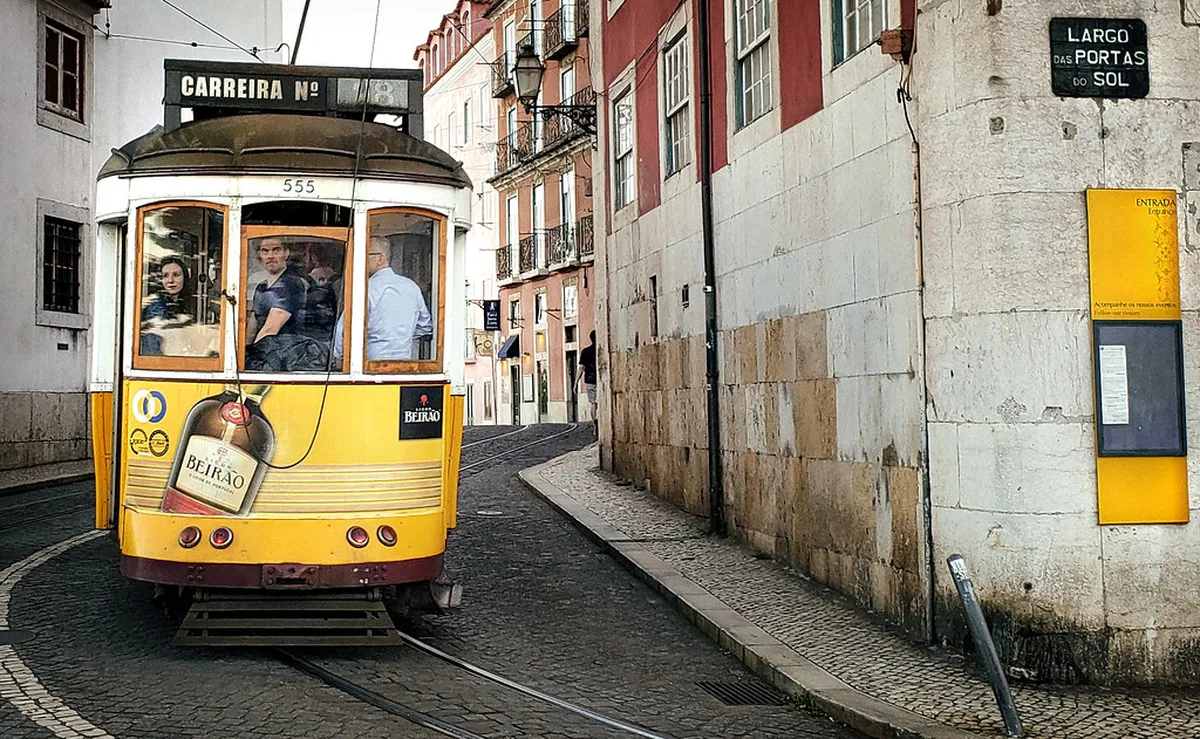 Historic Tram 28 navigating Lisbon's narrow cobblestone streets through Alfama