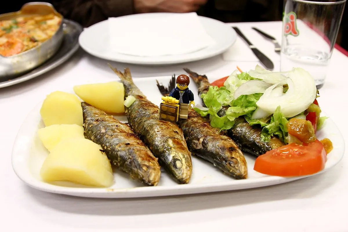 Fresh grilled seafood and sardines served at a Lisbon waterfront restaurant with rustic tableware