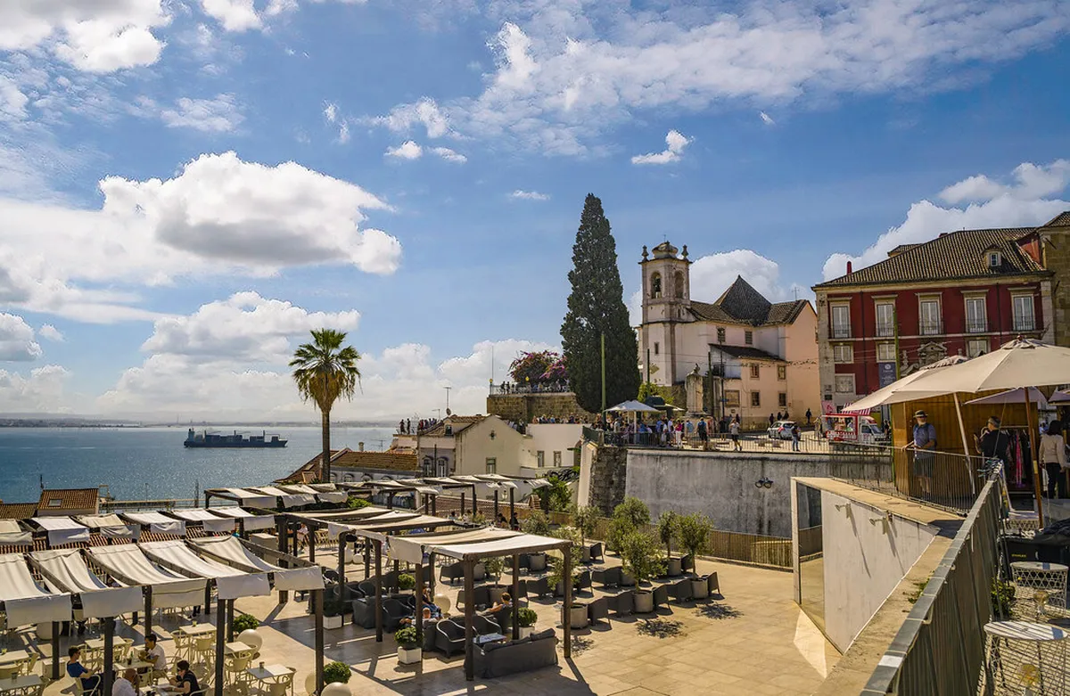 Panoramic view from Miradouro das Portas do Sol over Lisbon's Alfama rooftops and the Tagus River at golden hour