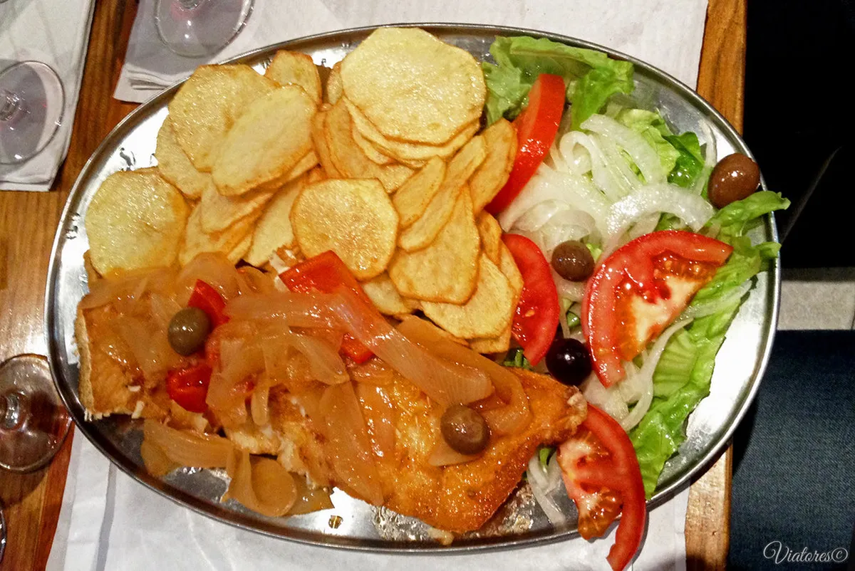 Traditional Lisbon bacalhau dish served at a fado restaurant alongside local Portuguese wine