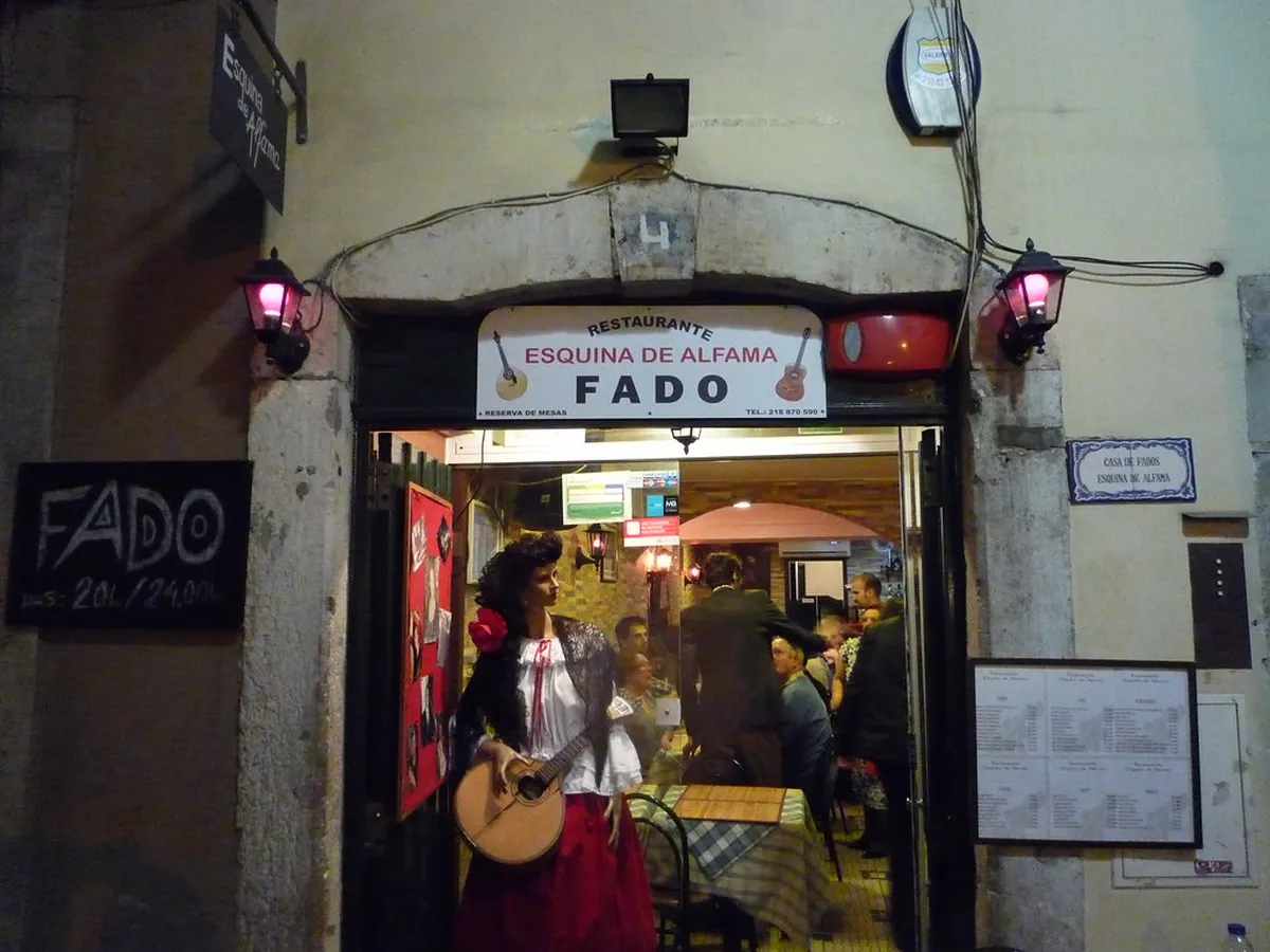 Intimate Lisbon fado bar interior with dim lighting and musicians performing for a small seated audience