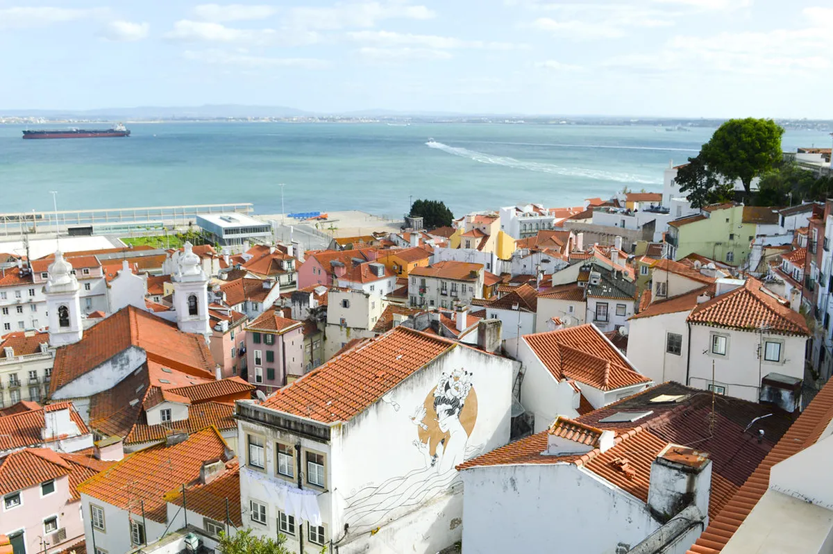 Scenic view over Alfama rooftops and the Tagus River from a Lisbon hotel terrace at dusk