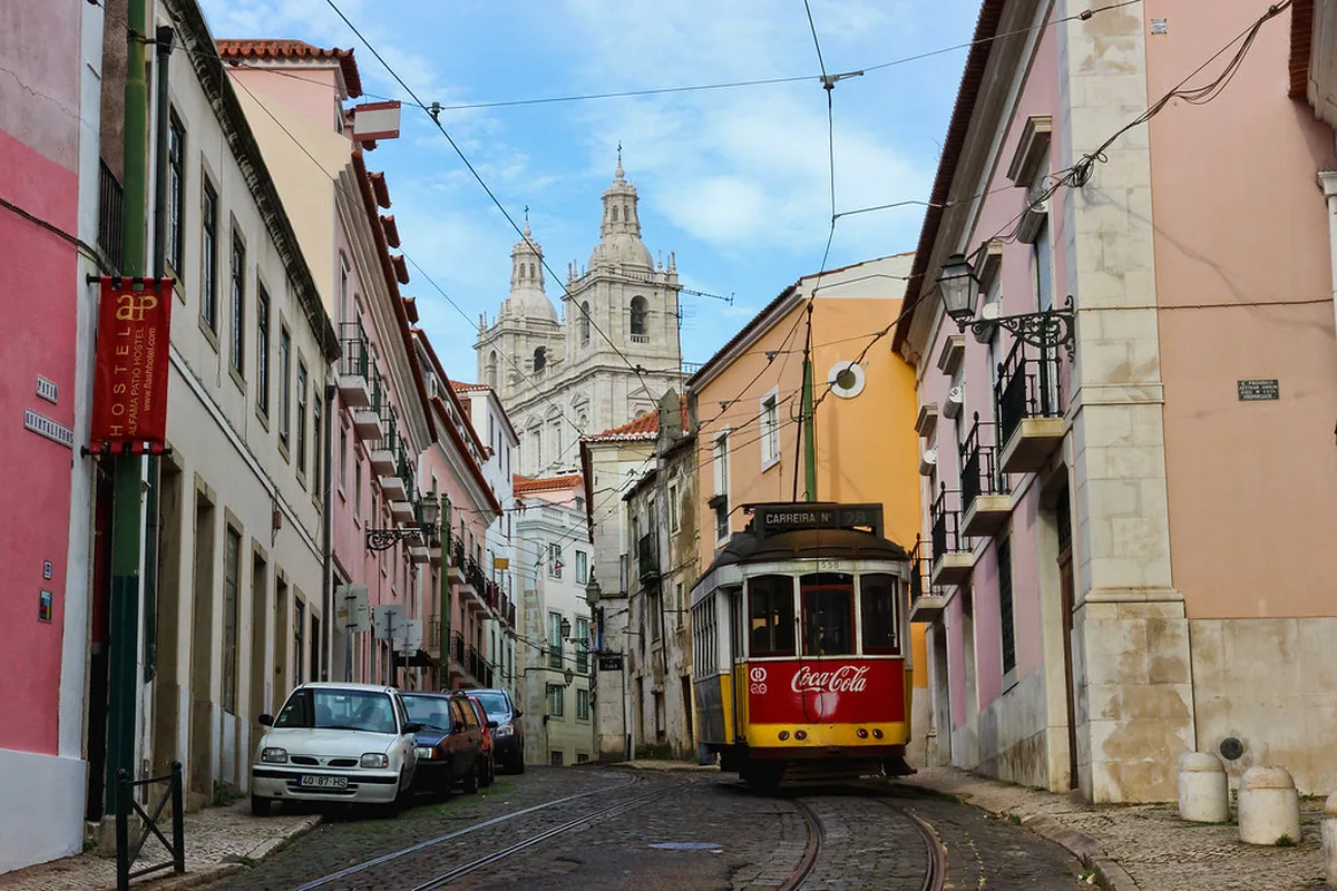 Narrow cobblestone street in Lisbon Alfama neighbourhood with colourful tiled buildings