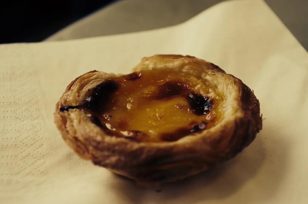 Golden Lisbon Pastel de Nata custard tarts on a bakery tray, a classic Portuguese sweet street food treat