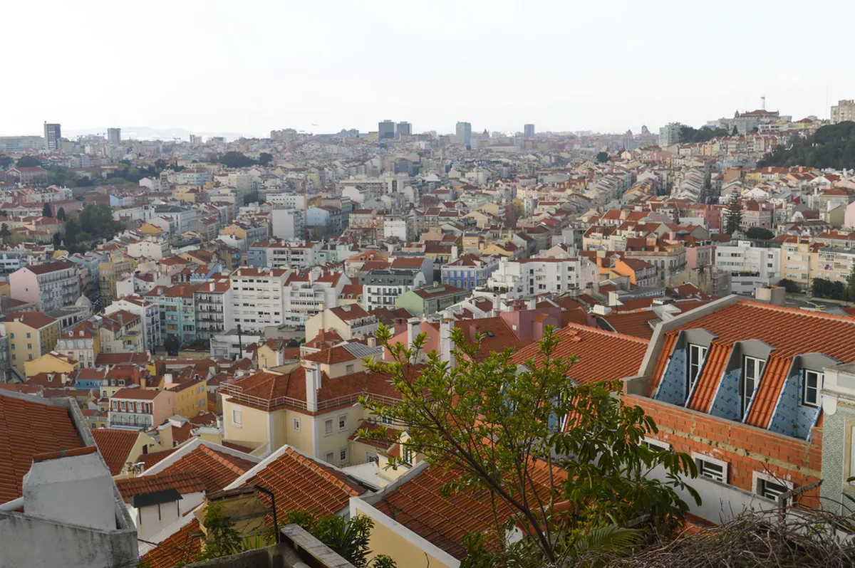 Sweeping Lisbon panorama from Miradouro da Senhora do Monte at dusk with city lights beginning to glow