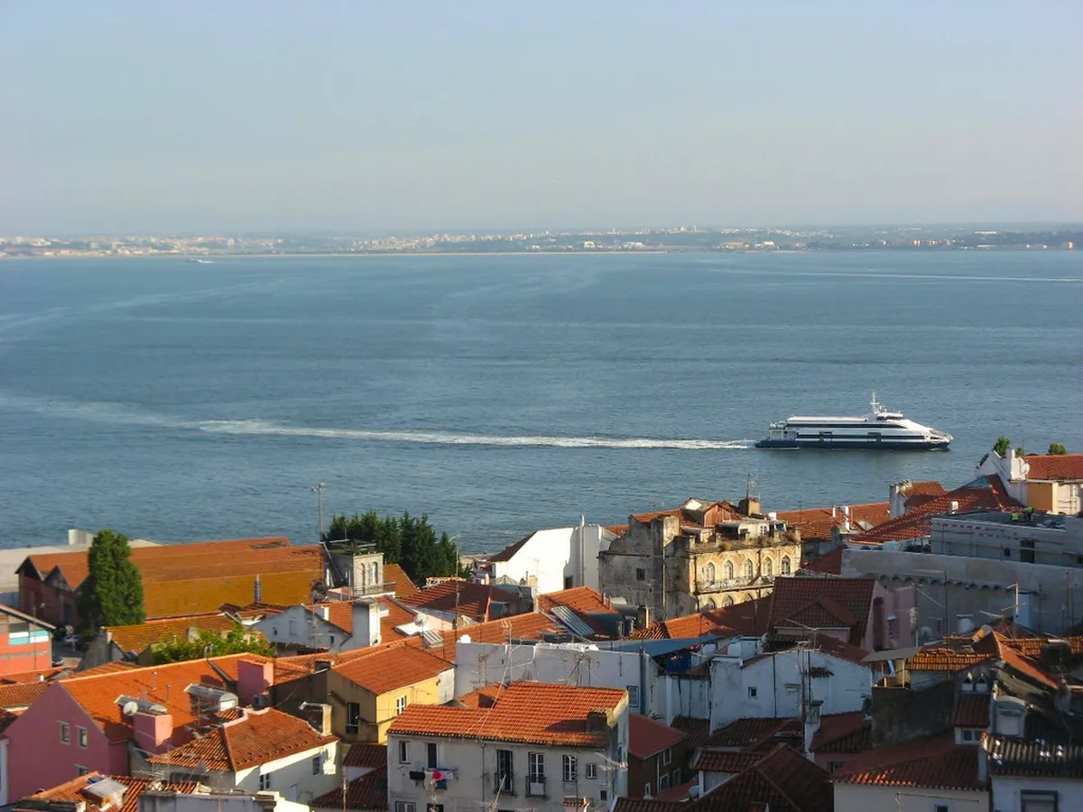 Classic Lisbon tram passing along a scenic route with views towards the Tagus River waterfront