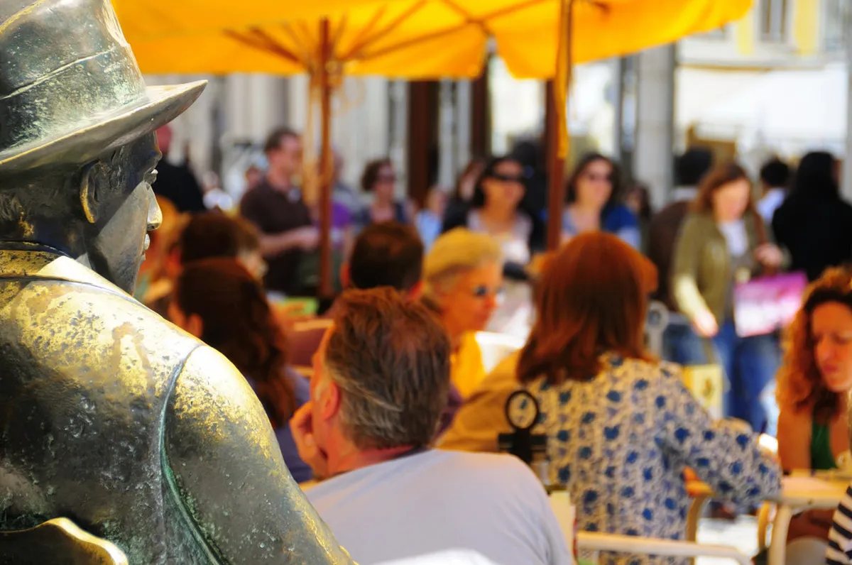 Visitors gathered at Café A Brasileira in Lisbon's Chiado district, with Fernando Pessoa bronze statue outside