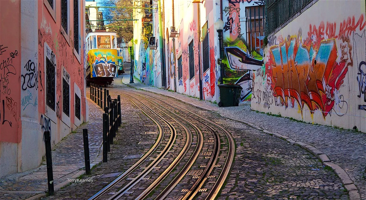 Cobblestone street in Lisbon Bairro Alto neighbourhood with colourful building facades and pedestrians at dusk