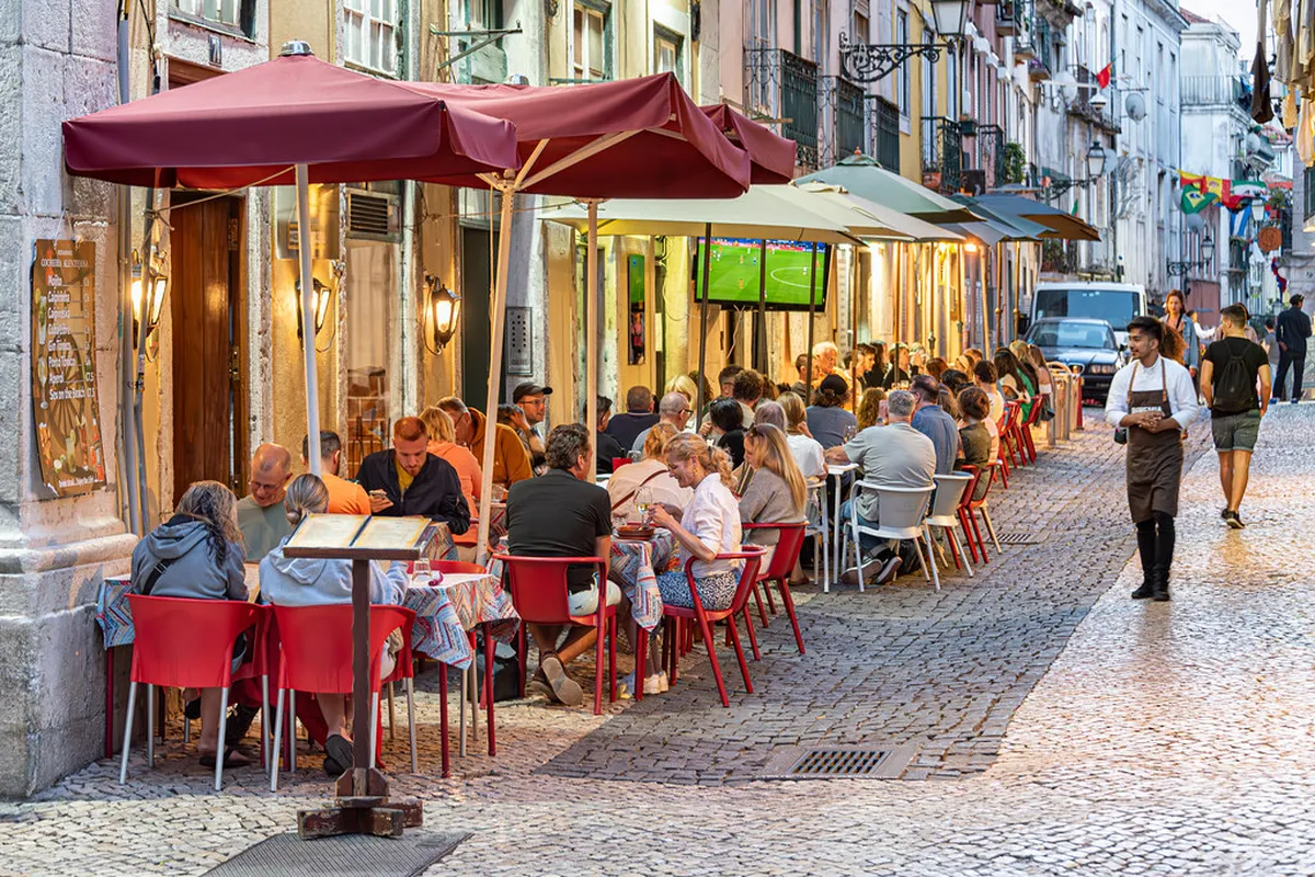 Warm-lit interior of a Lisbon Bairro Alto bar with vintage decor and locals enjoying drinks on a weeknight