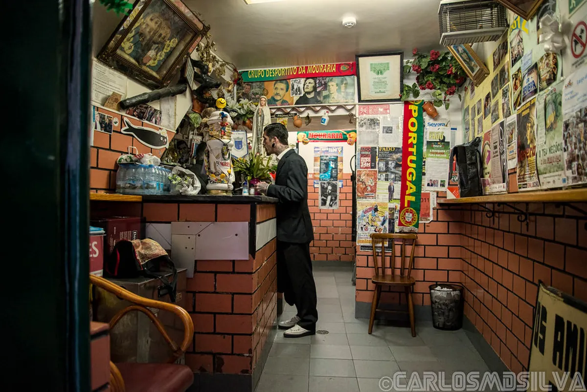 Cozy Fado bar interior in Lisbon with traditional decor and guitarists performing for a small intimate crowd