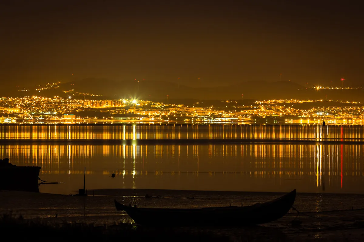 Golden sunset light over the Tagus River in Lisbon with the 25 de Abril Bridge in the distance