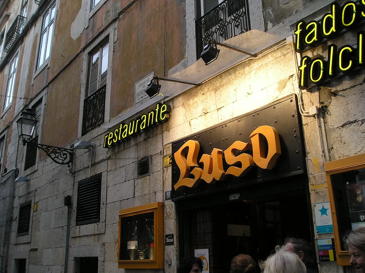 Intimate Fado performance in a dimly lit Lisbon venue with a singer and Portuguese guitar player on stage