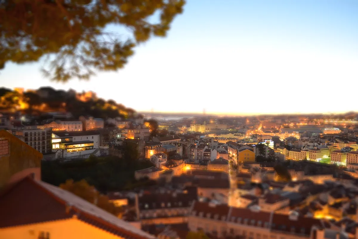 Panoramic view from a Lisbon miradouro viewpoint overlooking terracotta rooftops and the River Tagus