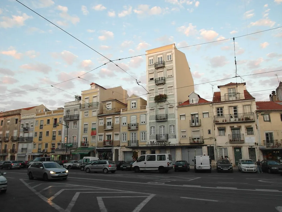 Cobblestone street in the Largo da Graça area of Lisbon lined with traditional tiled buildings and terracotta rooftops