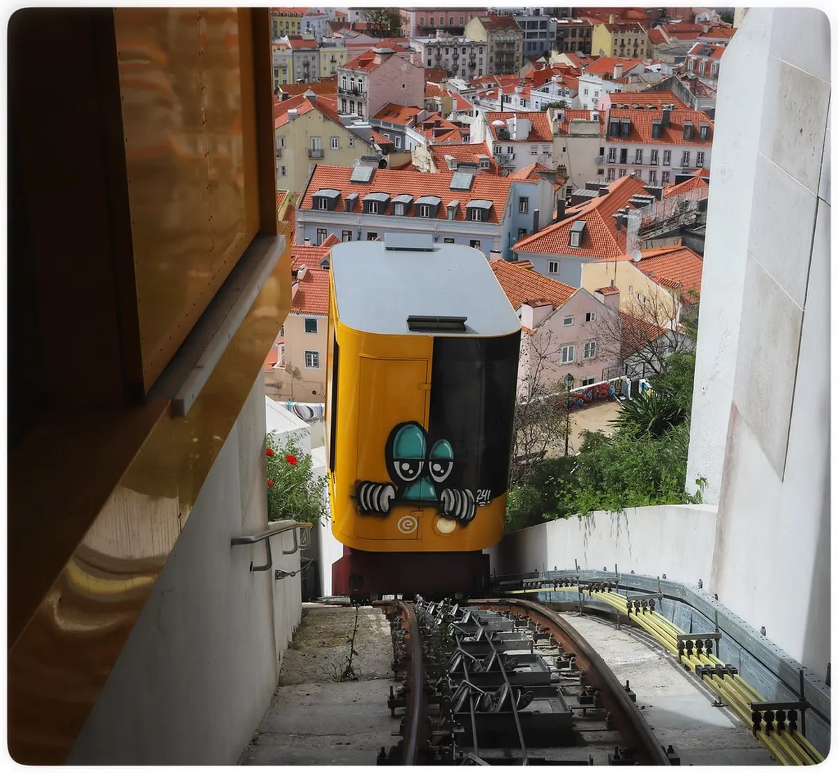 Lisbon Bica funicular ascending a steep hillside street between colourful neighbourhood buildings