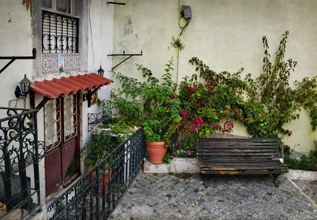 Lisbon Alfama district courtyard with tiled walls and narrow cobblestone alley leading to a sunlit hidden patio