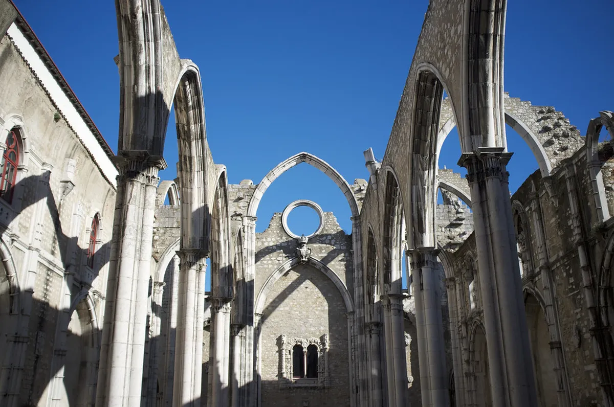 Lisbon Carmo Convent roofless gothic nave with stone arches standing against a bright blue sky