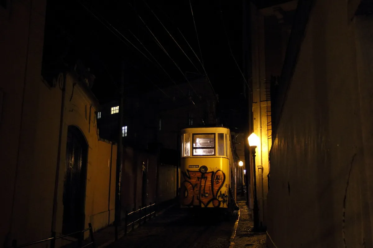 Vibrant Lisbon Bairro Alto street at dusk with warm lights spilling from traditional taverns and lively local atmosphere