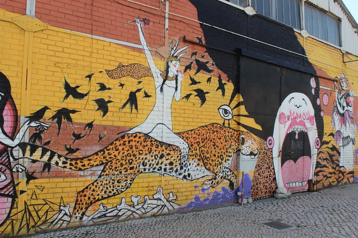 Colorful Lisbon graffiti mural covering an entire building wall with bold geometric shapes and figures