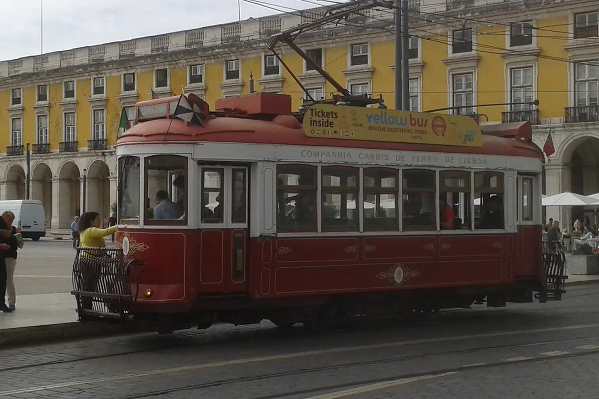 Vintage yellow Lisbon tram on a steep historic street lined with traditional tiled buildings