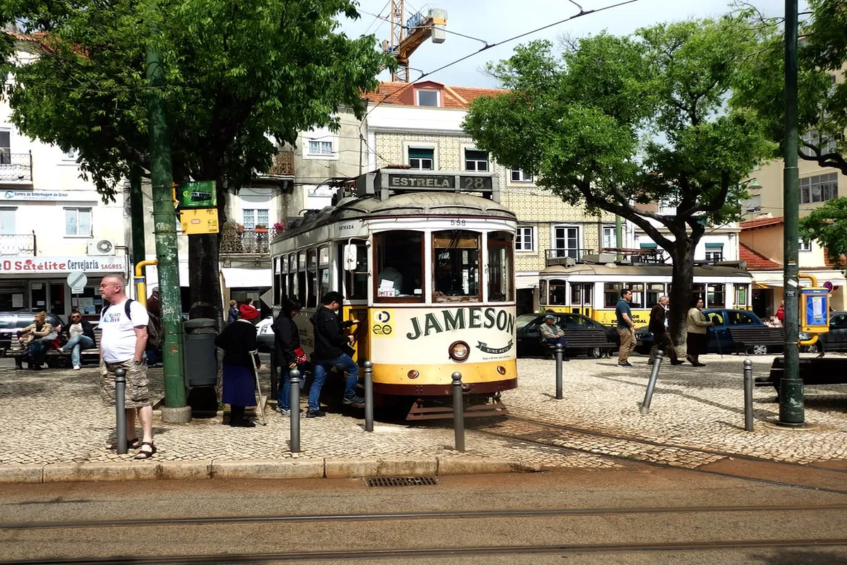 Lisbon vintage yellow tram rounding a tight cobblestone corner during the scenic 28E journey