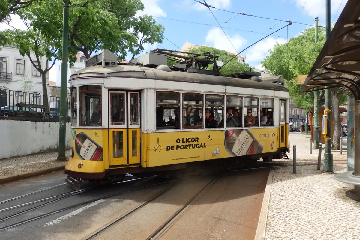 Modern Articulado tram 15E running along Lisbon's riverfront towards the Belém district