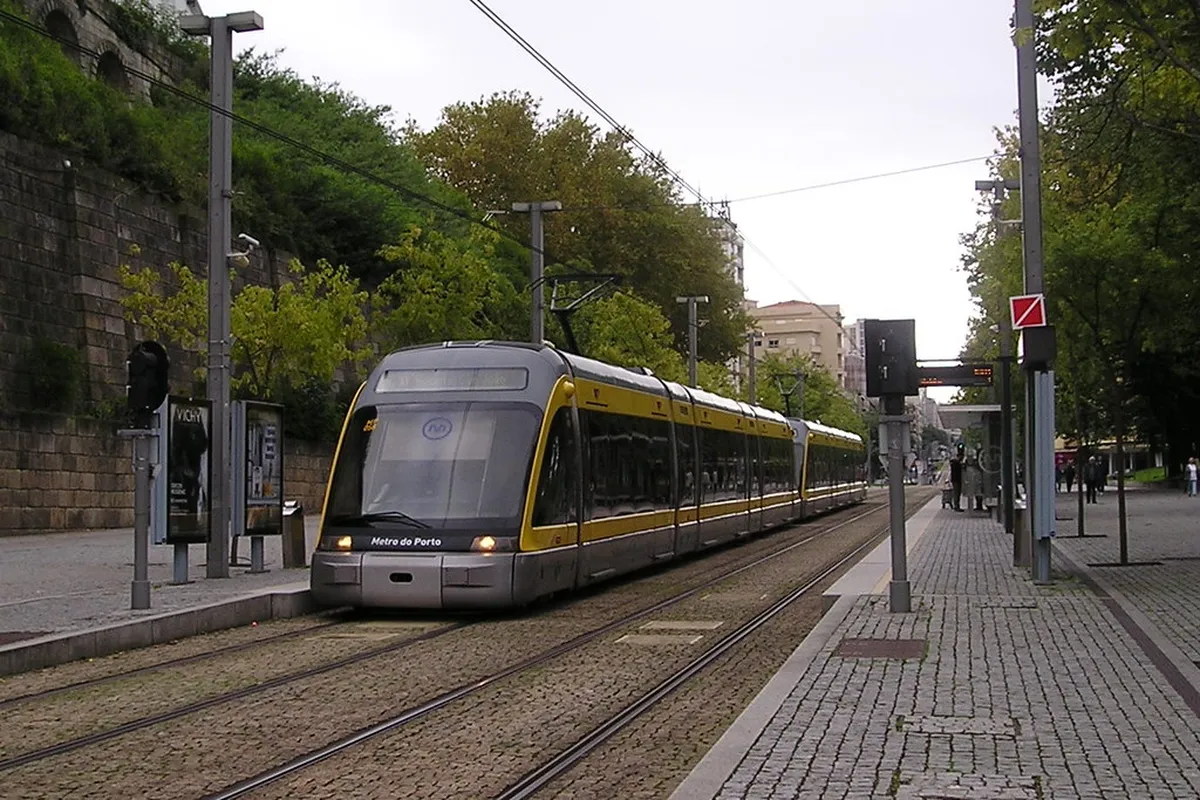 Porto vintage tram travelling through a narrow cobblestone street lined with traditional buildings in the city centre