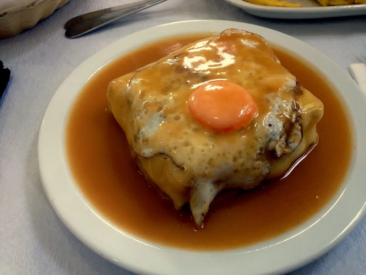 Traditional Porto Francesinha sandwich served on a plate, the iconic local dish with its signature rich sauce