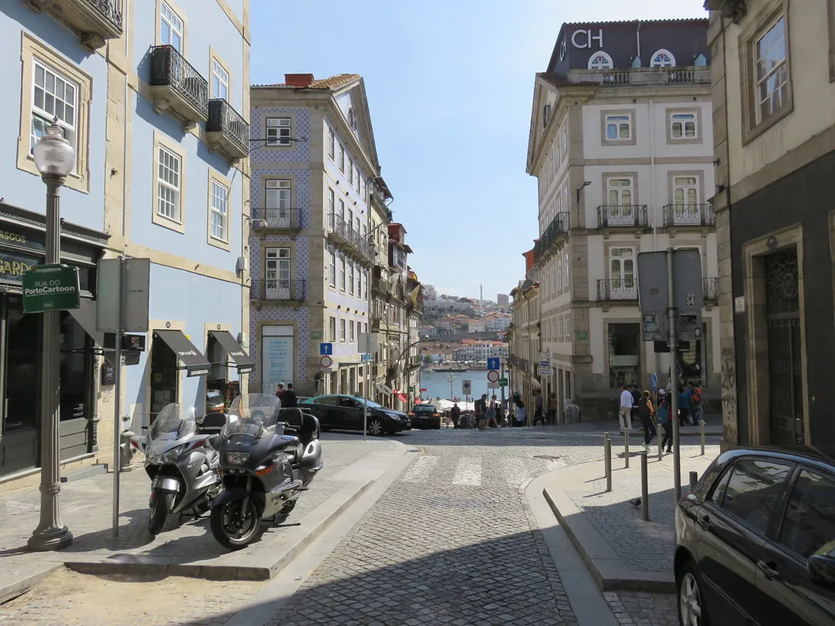 Bustling street scene in Porto's Baixa district lined with historic buildings, cafes, and local shoppers