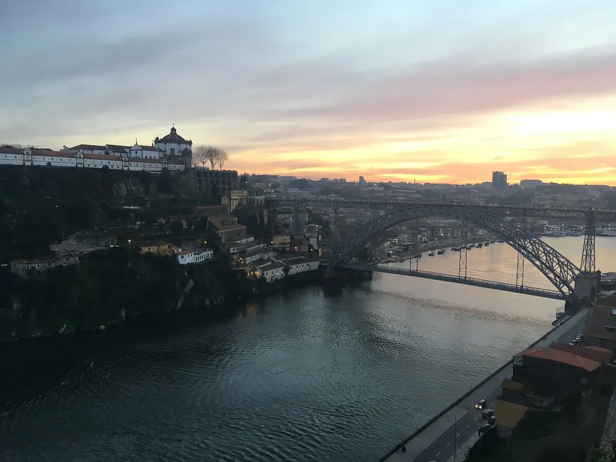 Panoramic Porto skyline along the Douro River with the illuminated Luís I Bridge reflected on the water at dusk