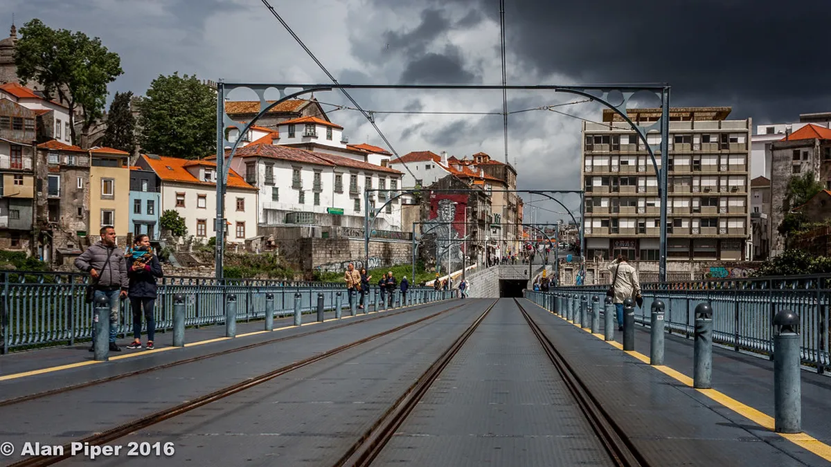 A vintage Porto tram travelling through narrow cobblestone streets lined with traditional azulejo-tiled buildings