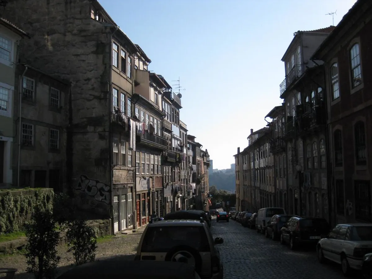 Pedestrians walking along a narrow Porto historic street with colourful facades and traditional stone paving