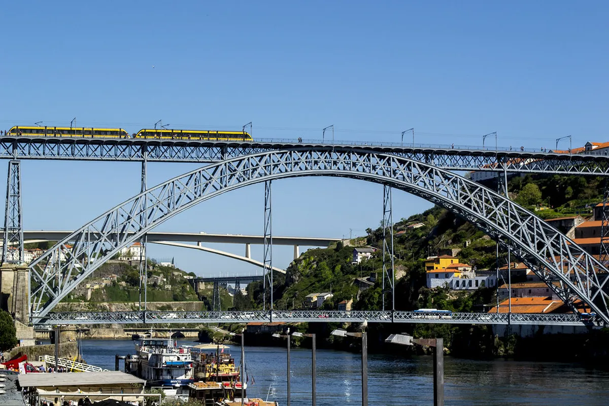 Vintage Porto tram travelling along the scenic Douro River waterfront with colourful riverside buildings in the background