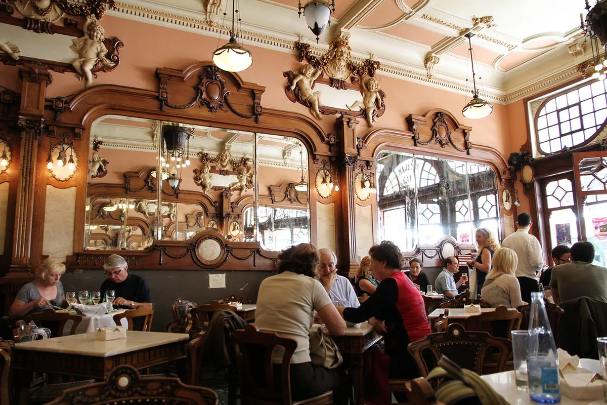 Cosy Porto cafe interior with warm lighting, marble tables and vintage tiles typical of historic cafes in the city