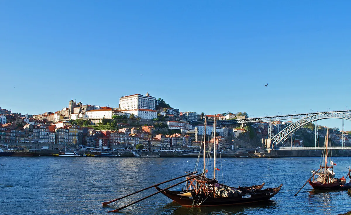 Porto wine lodge barrels and riverside lodges in Vila Nova de Gaia with the Dom Luís I Bridge visible in the background