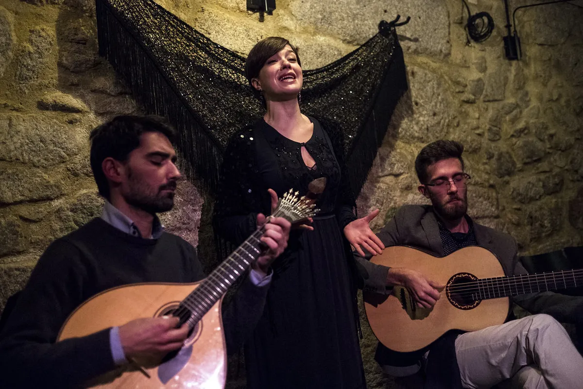 Porto Fado performance in an intimate venue with musicians playing traditional Portuguese guitar in dim warm light