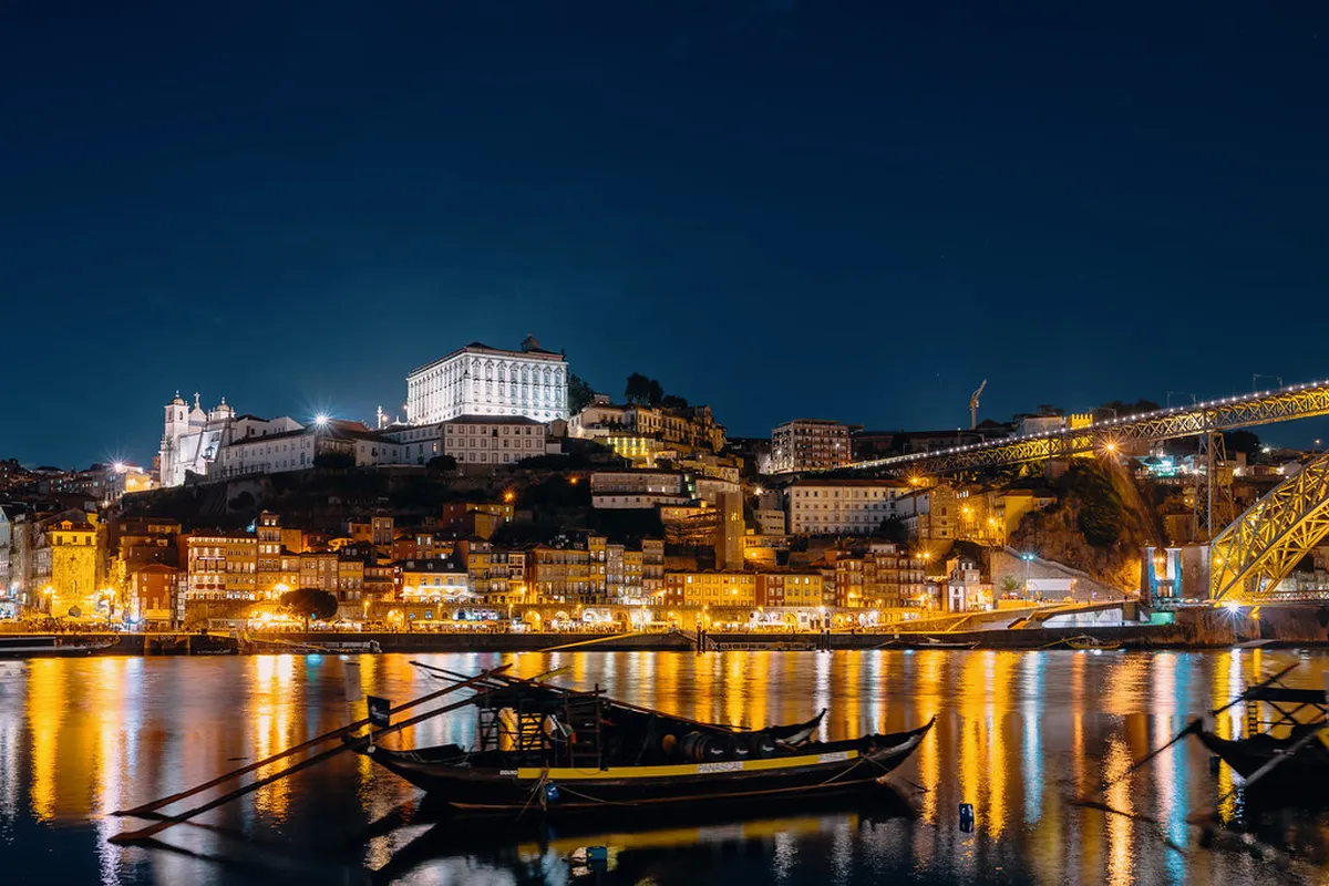 Porto Ribeira district cobblestone street at night with warm street lighting and people enjoying the lively atmosphere