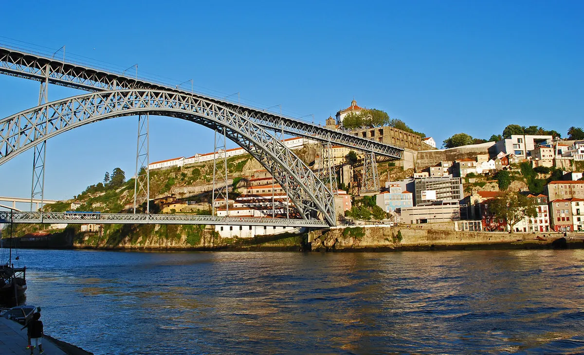 The iconic Dom Luís I Bridge spanning the Douro River in Porto at golden sunrise hour